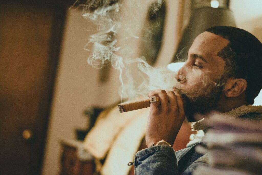 A cigar aficionado enjoying a smoke in a room.
