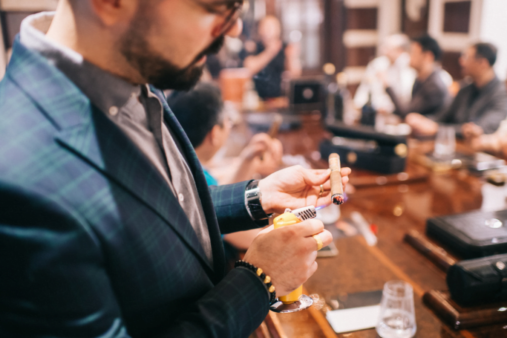 A man in a suit lighting a cigar.