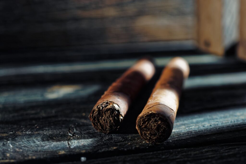 Two cigars, a popular tobacco product enjoyed by many, are elegantly displayed on a rustic wooden table.