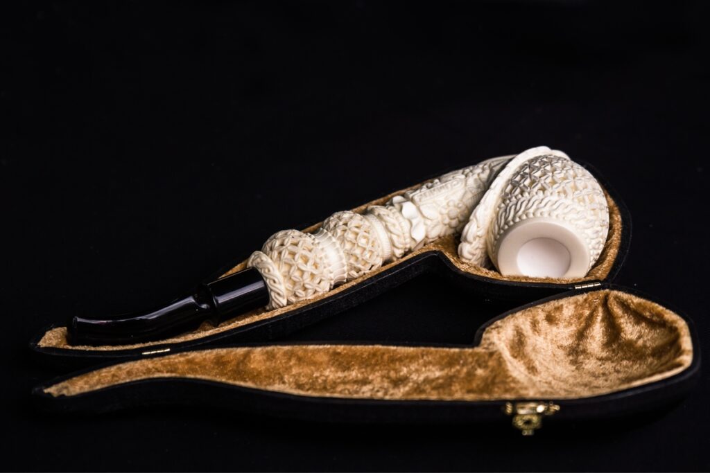 A classic smoking pipe, housed in a sleek leather case, showcased against a black background.