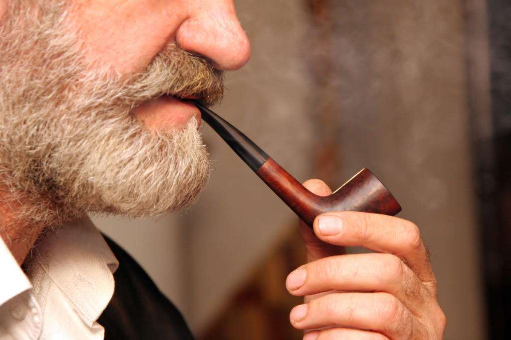 Man with a white beard smoking a pipe.