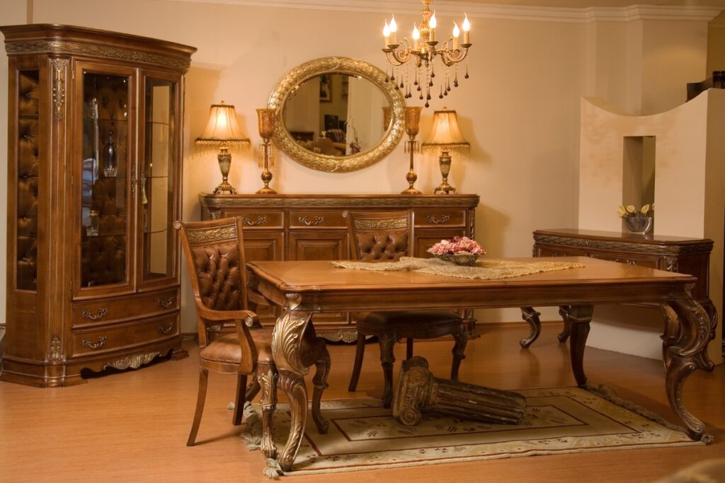 A traditional dining room with a wooden table, chairs, a decorative cabinet, a sideboard, a chandelier, and an ornate mirror. A vase with flowers sits on the table. Elegantly classical décor hints at its dual function as a refined home smoking lounge.