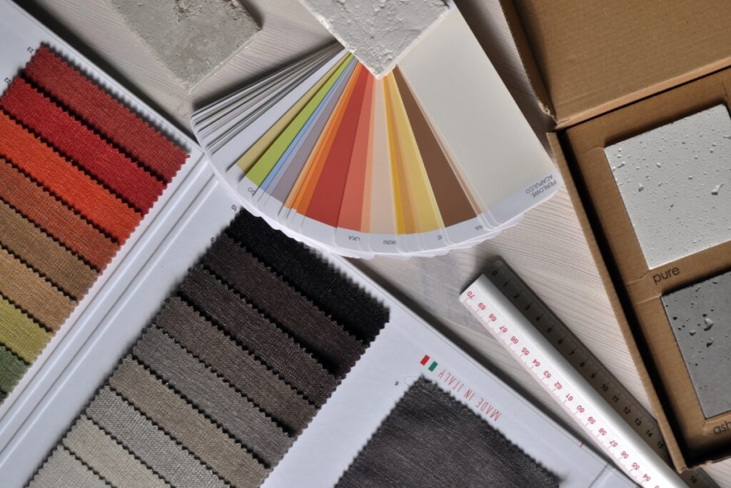 A variety of color swatches, fabric samples, and texture samples are displayed on a table next to a ruler and cardboard box, perfect for designing your ideal home smoking lounge.